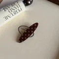 Vista detallada de una pinza para el pelo de acetato marrón con lunares en fondo crema - Clip de Pico de Pato Ovalado / Clip de Presión Ovalado Café