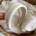 Detailansicht der eleganten plissierten Textur und des breiten weißen Satin-Stirnbandes. - Milchweiß