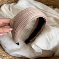 Detailansicht eines hellrosa gefalteten Satin-Stirnbands mit einer feinen Rippenstruktur - Champagner