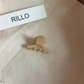 Primer plano de una pequeña pinza para el pelo de acetato crema sobre tela texturizada - Pinza de Pelo Pequeña / Blanco lechoso