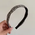 Detailed shot of a classic black and white plaid twisted headband held by hand - Milk Tea Black