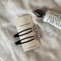 Detailansicht der Haarspangen mit kontrastierenden Knöpfen und blauem Karomuster - Blau Gestreifter Knopf-Stil / 2er-Pack / Blau Gestreifter Knopf Schwarze Haarklammer