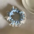 Detail van een elegante lichtblauwe scrunchie met crème kant en parels. - Blauw Haarelastiekje met Meerdere Parels