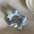 Detail shot of light blue scrunchie with large white pearl on textured background - Blue Pleated Single Pearl Hair Tie