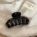 Detail macro view of a large glossy black dragon-bone hair claw clip on linen fabric. - Black
