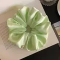Detailed macro view of a light green satin scrunchie showing elegant pleated fabric - L / Green