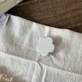 Detailed view of a matte flower-shaped hair clip with wer wer engraving on white fabric - 2.5cm / Creamy White Flower Hair Clip