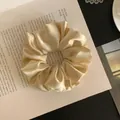 Close-up of champagne satin scrunchie with bow detail on open book background. - S / Yellow