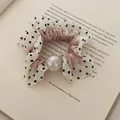 Elegante roze scrunchie met stippen en een grote iriserende parel op een open boek - Roze Haarelastiekje met Zwarte Stippen en Parel