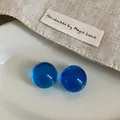 Detailaufnahme der leuchtend blauen, transparenten Harz-Ohrstecker auf Leinen-Hintergrund - Blau