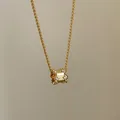 Close-up van een gouden ketting met cilindervormige hanger en sprankelende kristallen - Goud