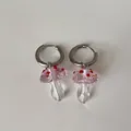 Nahaufnahme von niedlichen Glaspilz-Ohrringanhängern in Pink und Klar auf weißem Grund. - Creolen-Stil / Rosa