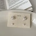 Close-up detail of firework shape and pearl stud earring set on a beige display card. - Style 34 Earrings