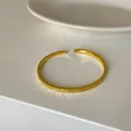 Nahaufnahme eines goldfarbenen strukturierten offenen Armreifs für Damen mit Glitzereffekt - Gold Armband (N4-30) / Gold