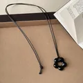 Vista dettagliata di un ciondolo a fiore in vetro nero su una collana minimalista in corda. - 70cm / Cordino Cerato Fiore Nero