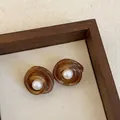 Close-up of vintage brown resin stud earrings with elegant white pearl center accents - Style 9 (925 Silver Post)
