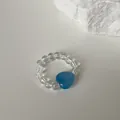 Detail of clear beaded elastic ring featuring a blue heart-shaped stone accent - Blue