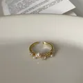 Nahaufnahme eines eleganten goldenen Rings mit Zirkon-, Perlen- und Muschelmotiven - Muschel Blumenstil / Gold