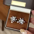 Detailed close-up of fireworks-inspired pearl and zircon stud earrings in a luxury brown box - Style 35 Earrings