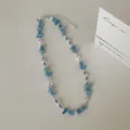 Detail van de ketting met natuurlijke aquamarijnsteen en parels op een wit oppervlak. - Stijl 1 Halsketting