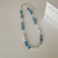 Detailopname van aquadmarijn natuursteen en parelkralen ketting op witte tafel - Stijl 2 Halsketting