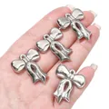 Detailopname van glanzende zilveren strikbedels in de hand gehouden voor de schaal. - Lintstrik / 5 Stuks/Verpakking (26x30mm) / Zilver