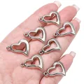 Close-up van zilveren hartvormige CCB-bedels in een hand voor het maken van sieraden - Hol Schuin Hart / 20 Stuks (17x22mm) / Zilver