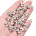 Detailopname van zilveren strik-bedeltjes in de hand voor DIY-kettingen en sieraden maken - Mini strikknotketting