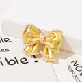 Primo piano dell'elegante spilla a fiocco dorata con perle su sfondo bianco pulito - Oro (J-106)