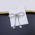 Detailed macro view of a silver bow brooch featuring sparkling rhinestone tassels and drops - Long Tassel Drip Style (A5-99) / Silver