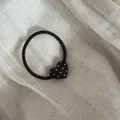 Detail einer schwarzen Herz-Haargummi mit weißen Punkten auf Leinenhintergrund - Herz Haargummi / Kaffee Herz Weißer Polka-Punkt