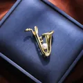 Close-up of a delicate gold saxophone brooch featuring a small lustrous white pearl - Saxophone Style (A15-131) / Gold