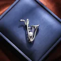 Detailed view of a silver saxophone brooch with a white pearl on a dark blue gift box - Saxophone Style (A15-132) / Silver