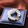 Detailed view of elegant pearl brooch with sparkling rhinestone butterfly on dark box. - Butterfly Rhinestone Round Style (A16-116)