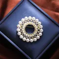 Close-up of elegant floral pearl brooch with sparkling rhinestones in blue gift box - Gold Round Garland (A16-112)