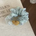 Detailed view of floral organza scrunchie featuring a yellow corduroy heart charm - Blue Floral Scrunchie With Heart