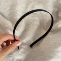 Nahaufnahme eines hochwertigen, minimalistischen schwarzen Satin-Haarreifs auf Leinen - Schwarz
