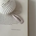 Close-up detail of a minimalist pink faux leather BB hair clip on a vintage book page - Teardrop Shape (4#) / Pure Pink