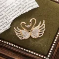 Elegant golden double swan brooch decorated with sparkling crystals and black stones - Double Swan Style (A15-104) / Gold