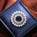 Elegant circular brooch with white pearls and sparkling rhinestones displayed on a blue box. - High-end Hollow Round Style (A16-113)