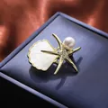 Dettaglio spilla a stella marina dorata con perla e cristalli su scatola - Stile Stella Marina e Conchiglia (A18-120)