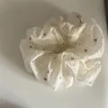 Close-up detail of a white fabric scrunchie with blue daisy embroidered flower patterns - Style 5 Large Scrunchie / White Camomile