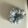Detailed view of a light blue daisy print fabric scrunchie with a white tag - Style 4 Small Scrunchie
