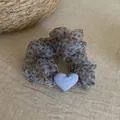 Close-up of a blue leopard print mesh scrunchie featuring a soft light blue heart charm. - Heart Scrunchie / Blue Leopard Heart