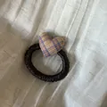 Detalle de un coletero con forma de corazón a cuadros sobre un fondo de tela suave - Lazo para el Pelo de Corazón a Rayas Amarillo y Azul
