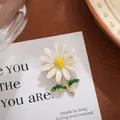 Detailed view of a white daisy brooch with yellow center and green leaves on gold plating - Little Daisy Flower Style (A19-65)