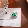 Detalle de broche de lujo con cristal verde esmeralda rectangular y halo resplandeciente - Estilo Plateado (A19-78) / Plateado