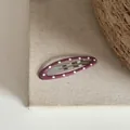Gros plan d'une pince à cheveux ovale violette à pois blancs sur un fond en lin naturel - Clip BB Ovale à Pois / Rose