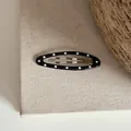 Vue détaillée d'une barrette ovale noire ornée d'un motif classique à pois blancs. - Clip BB Ovale à Pois / Noir