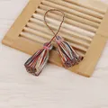 Gros plan d'un pendentif à pompons en coton multicolore fait main avec boucle tressée - Gland à Double Extrémité / Mélange de Couleurs Foncées